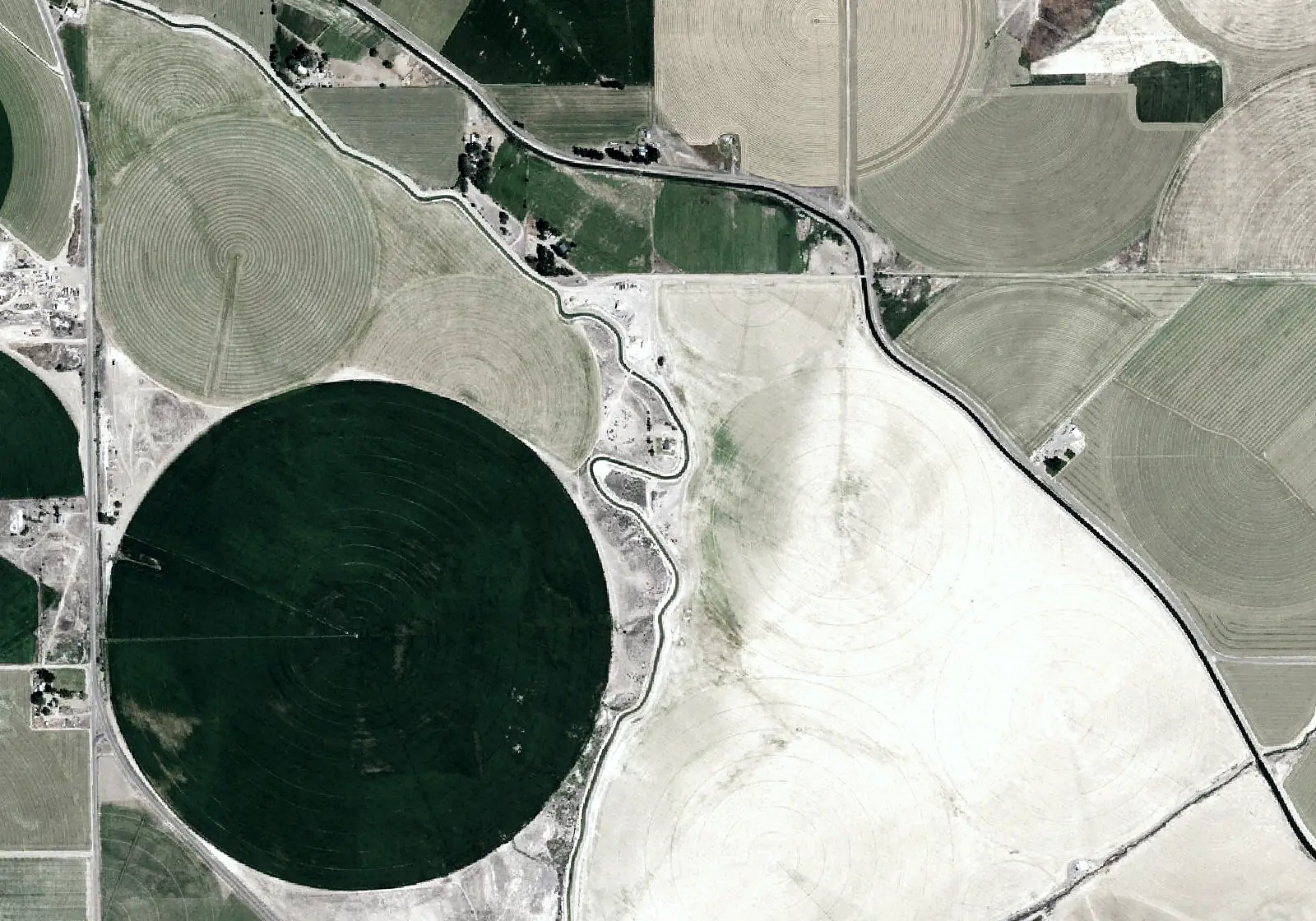 Aerial view: pivots and fields beside a river.