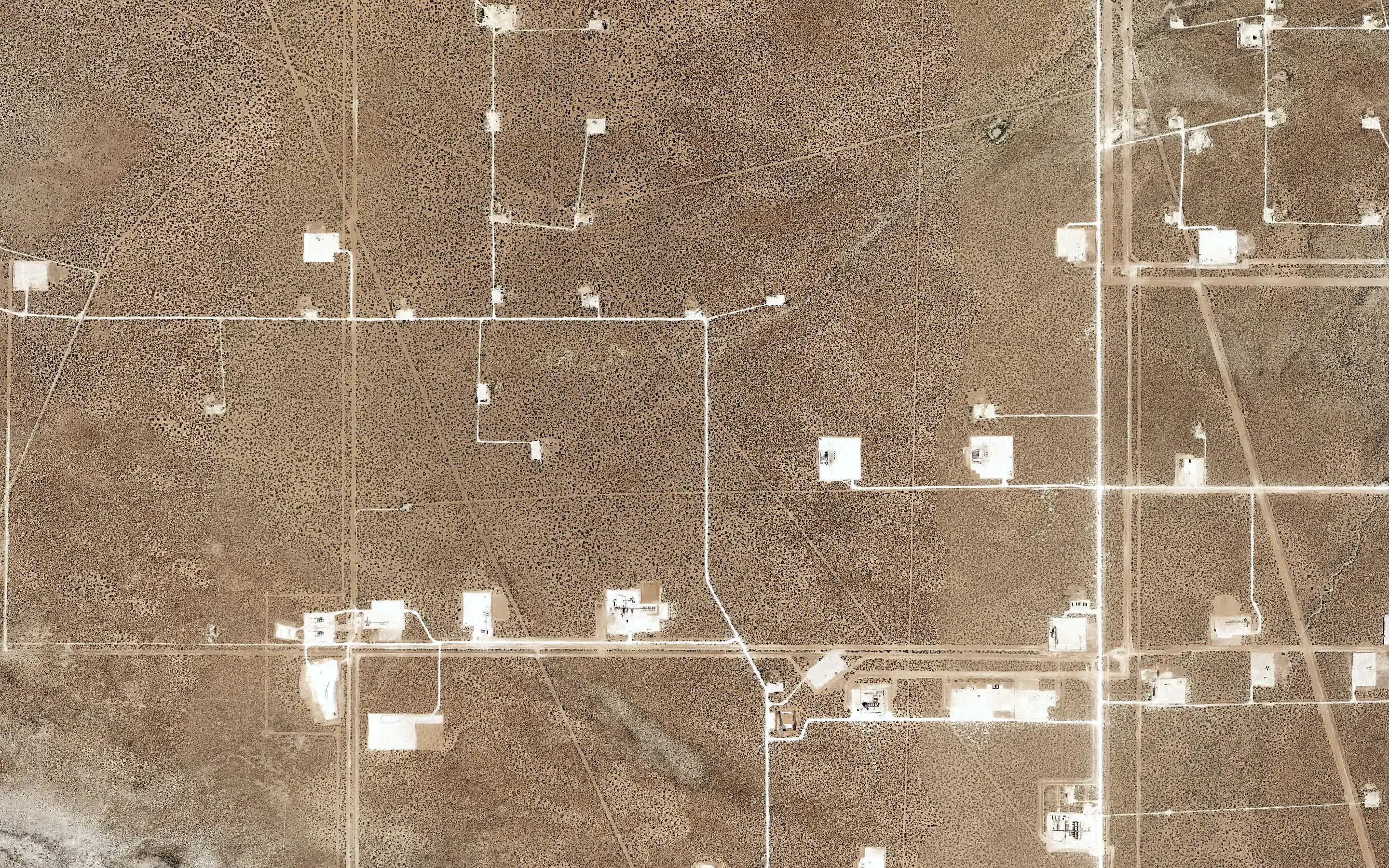 Aerial view straight down: well pads and roads on open range.