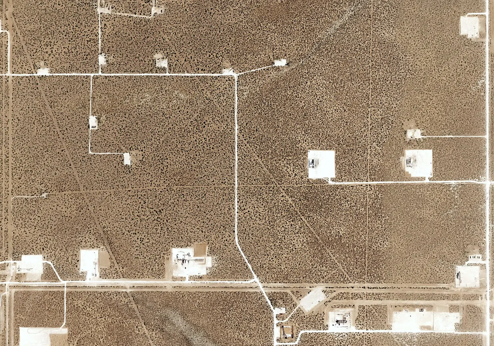 Aerial view: well pads and roads on open range.
