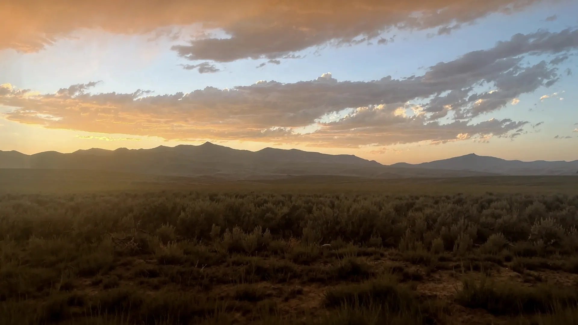 Sagebrush range at sunset below a mountain front.
