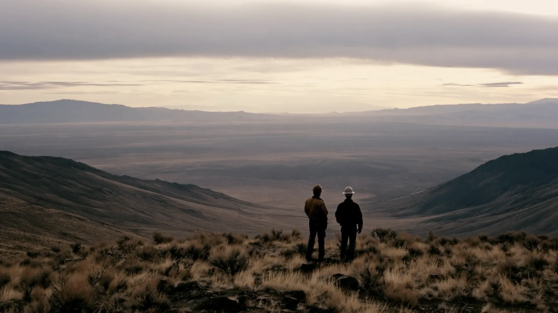Two people on a ridge looking out over a desert valley.